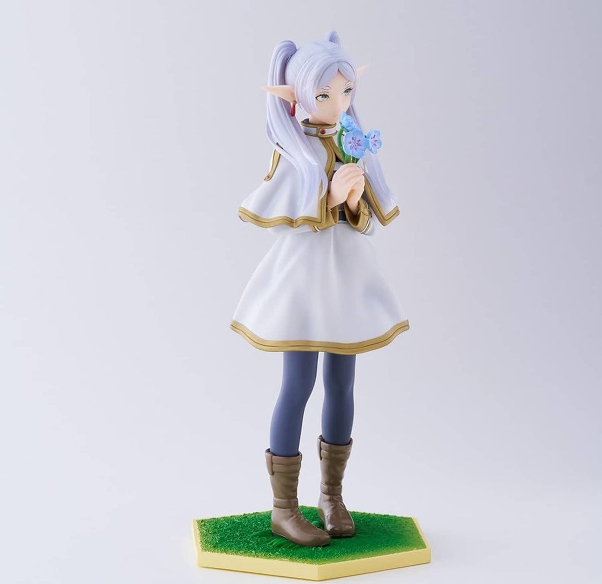 Standing character figurine with bouquet and lavender hair, white dress, blue leggings, green base.