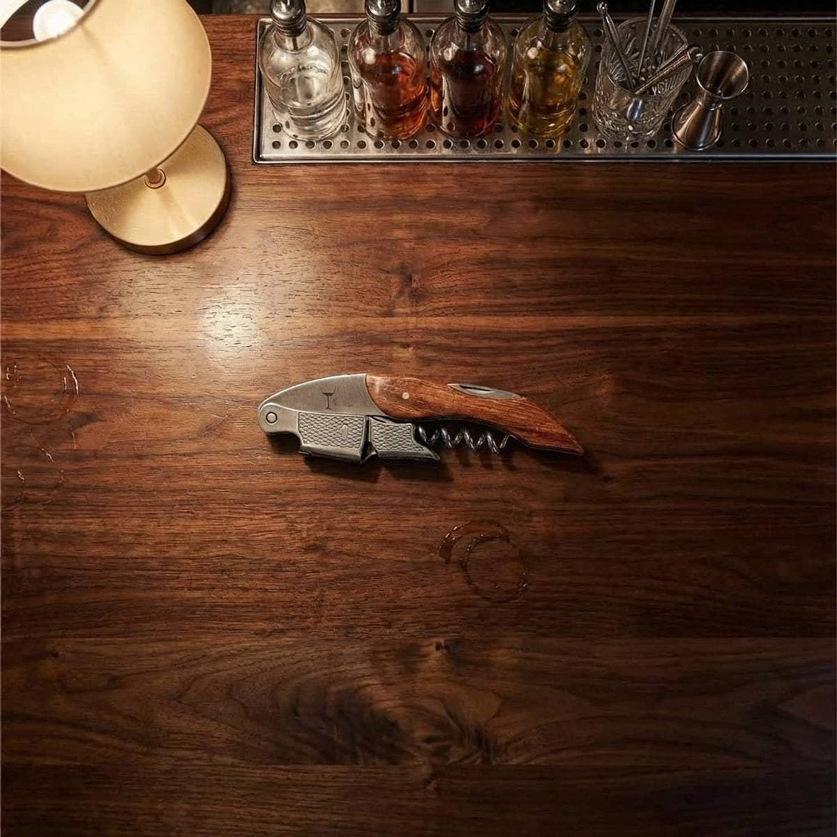 Stainless wine corkscrew with dark handle on a wooden bar surface