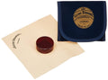Violin and viola rosin cake with blue cloth pouch, dark amber disc on paper