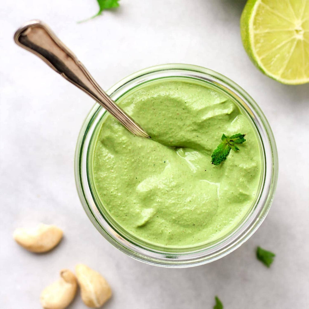 Jar of bright green lime powder paste with spoon, lime slices around it