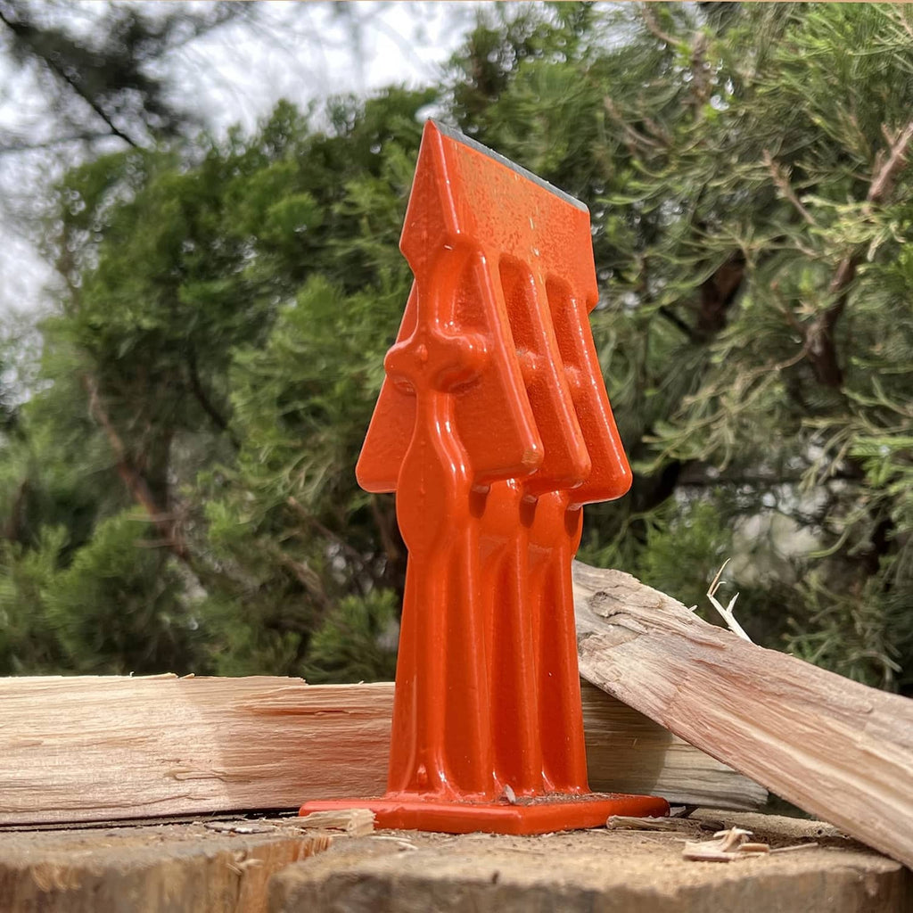 Orange log splitting wedge tool standing on stacked firewood logs