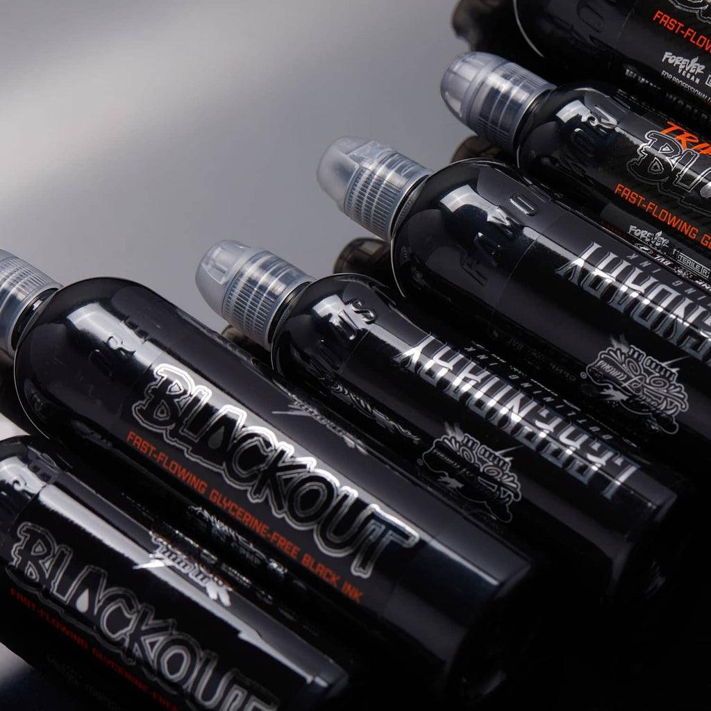 Multiple black tattoo ink bottles with clear caps in a diagonal row