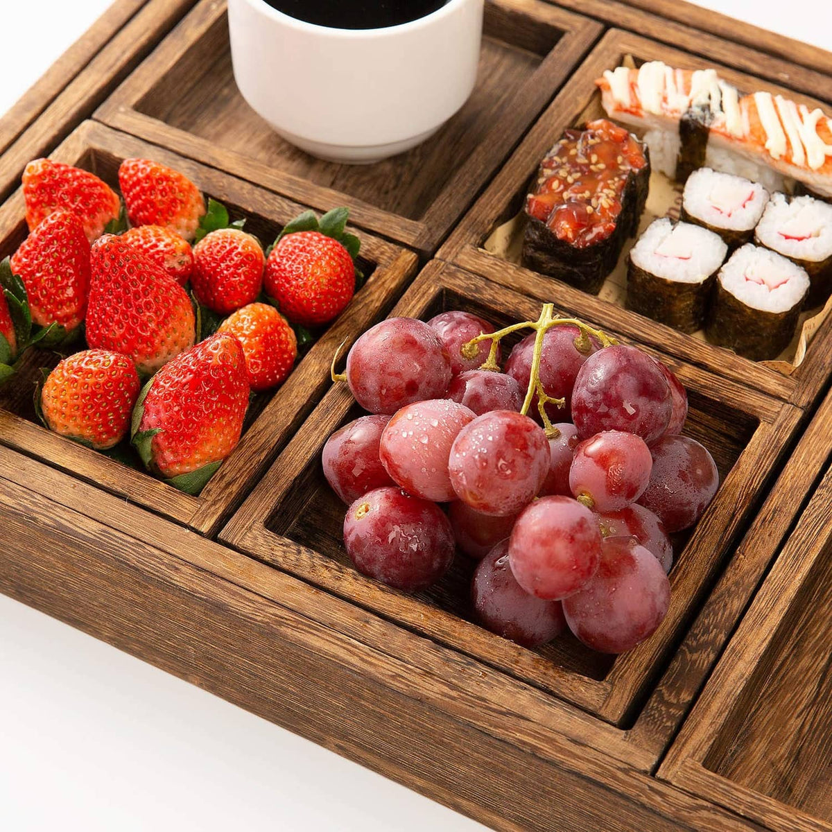 Rustic wooden serving tray with divided sections holding fruit and sushi