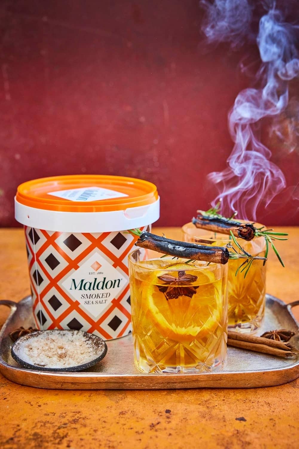 Smoked sea salt flakes bulk tub with orange lid on smoky tray