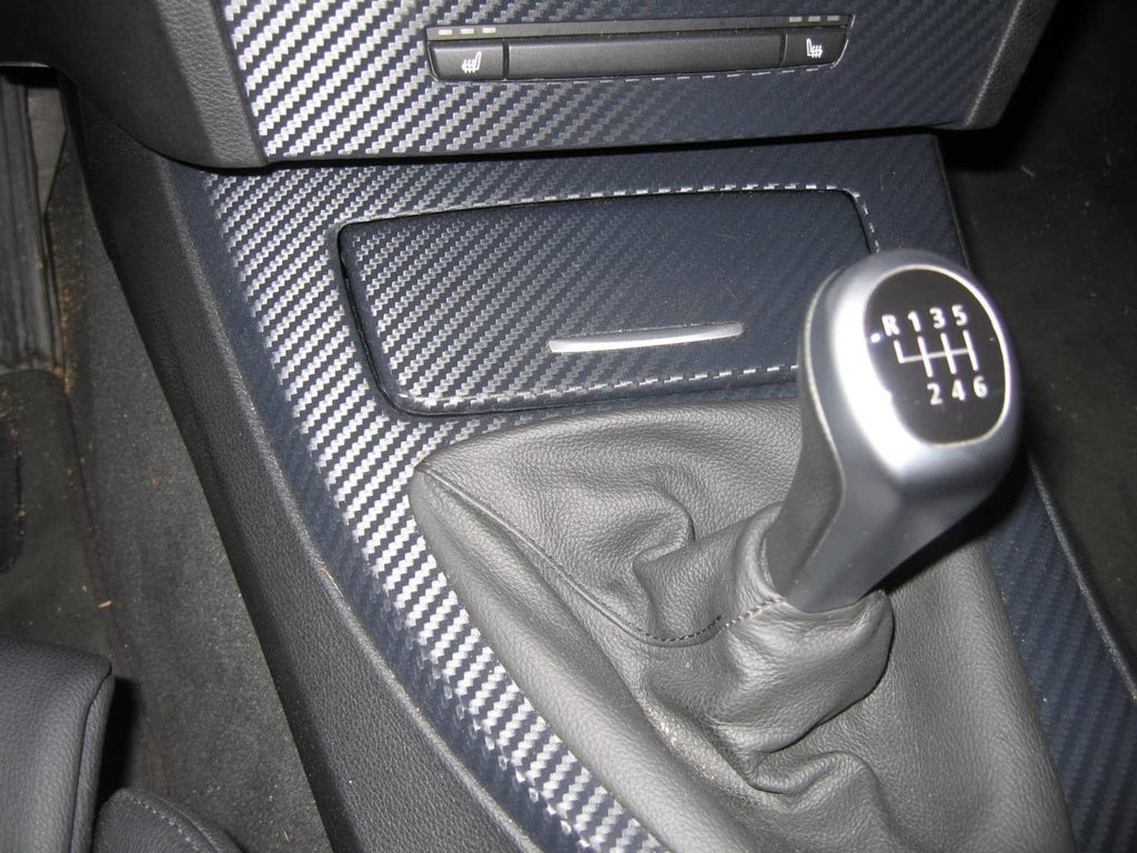 Black carbon fiber trim film applied on car dashboard panel near gear shifter