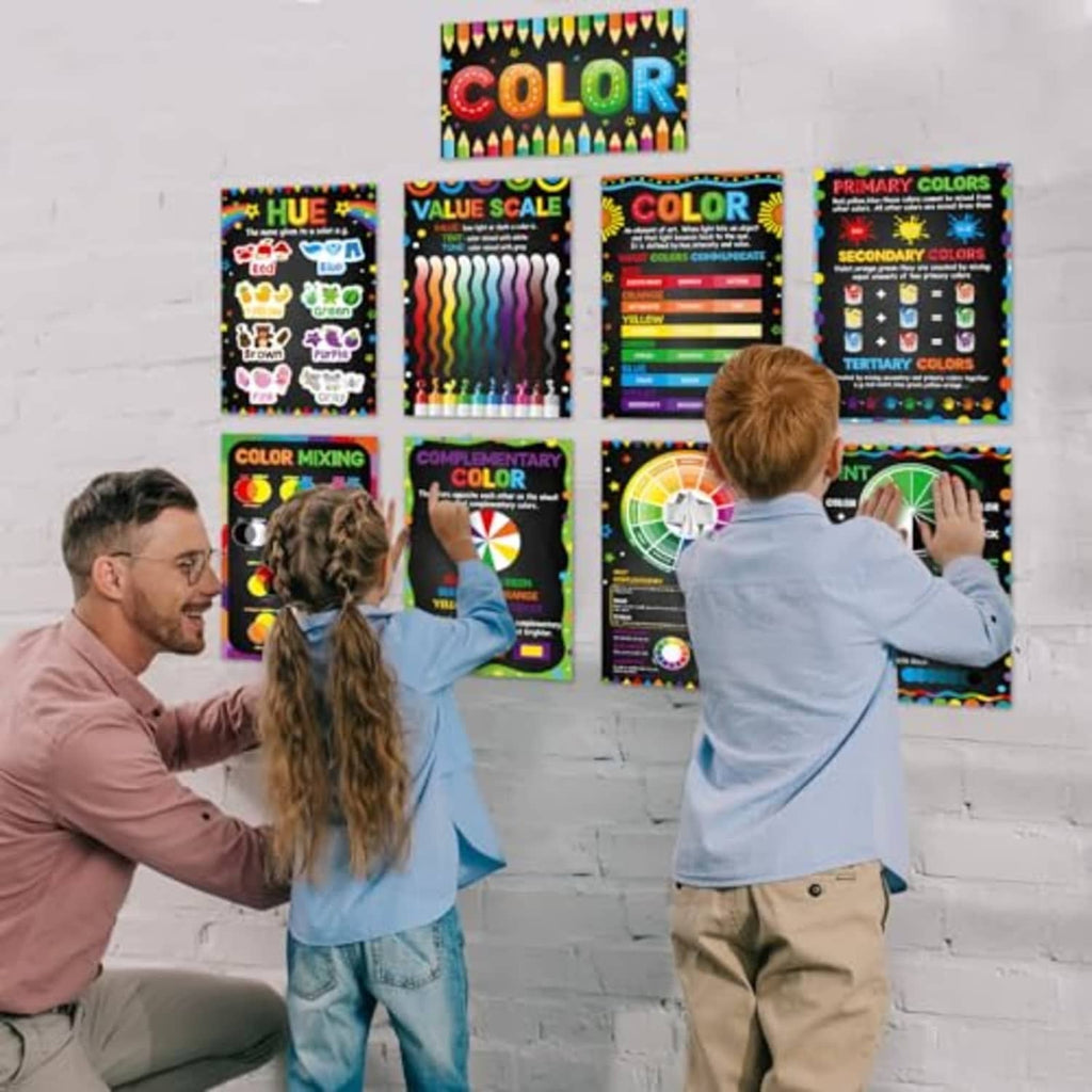 Color theory poster set held by students; laminated black charts with color wheels and scales