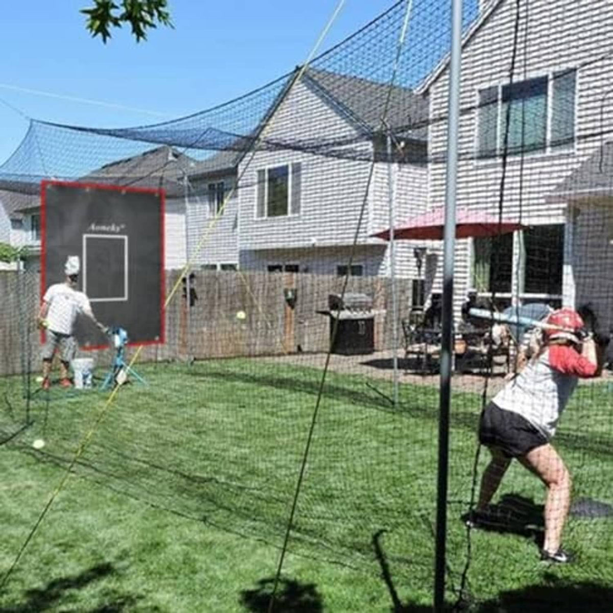Strike zone training backdrop with red border and white rectangle hanging in backyard yard