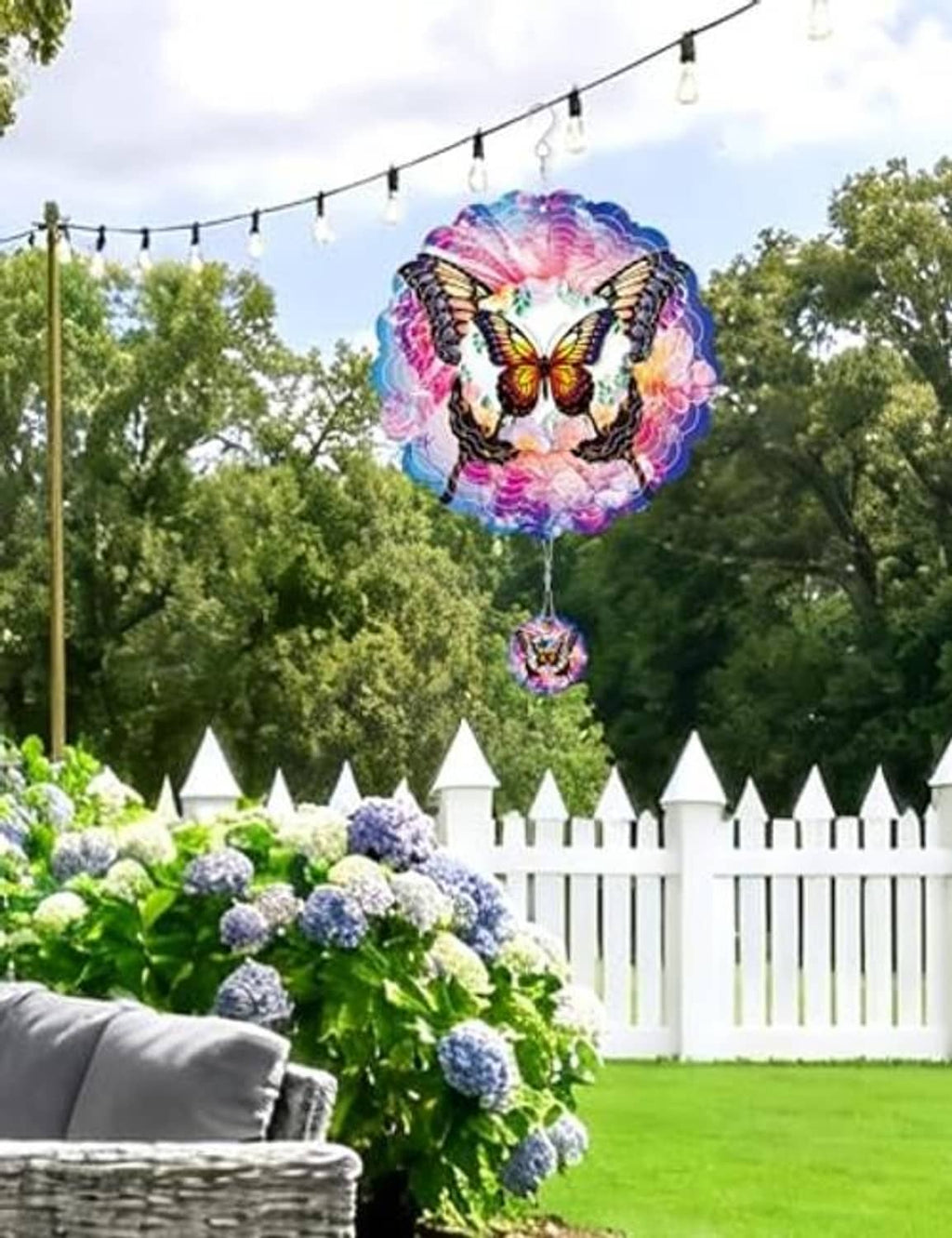 Purple butterfly wind spinner with hanging round pendant, layered metal blades outdoors