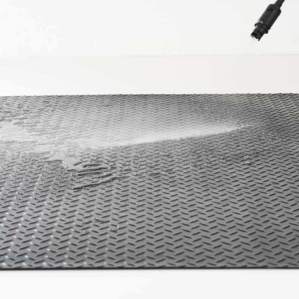 Gray diamond-plate mat surface close-up with raised traction ridges