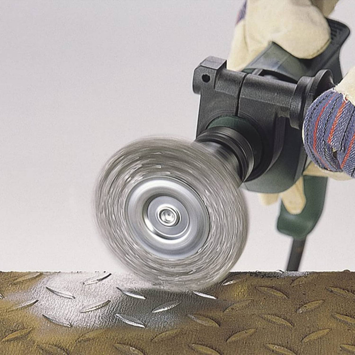 Wire drill brush wheel working on metal surface, circular steel bristles