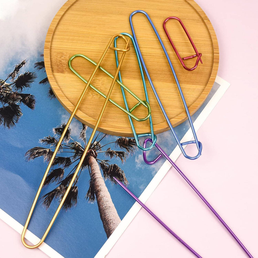 Assorted colored U-shaped knitting stitch markers on round wooden board
