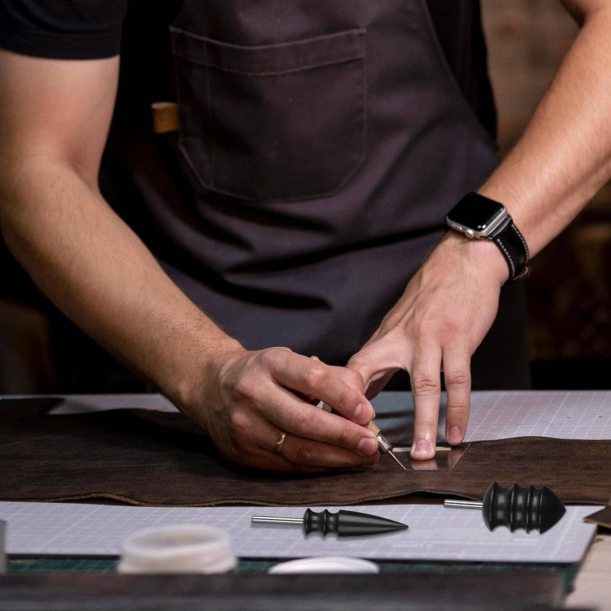 Leather crafter working with burnisher bits on a cutting mat and leather piece