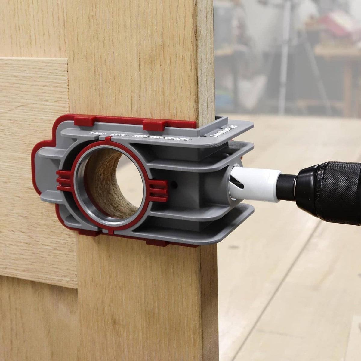 Door drilling jig clamped to wood with drill bit positioned for a lock cutout