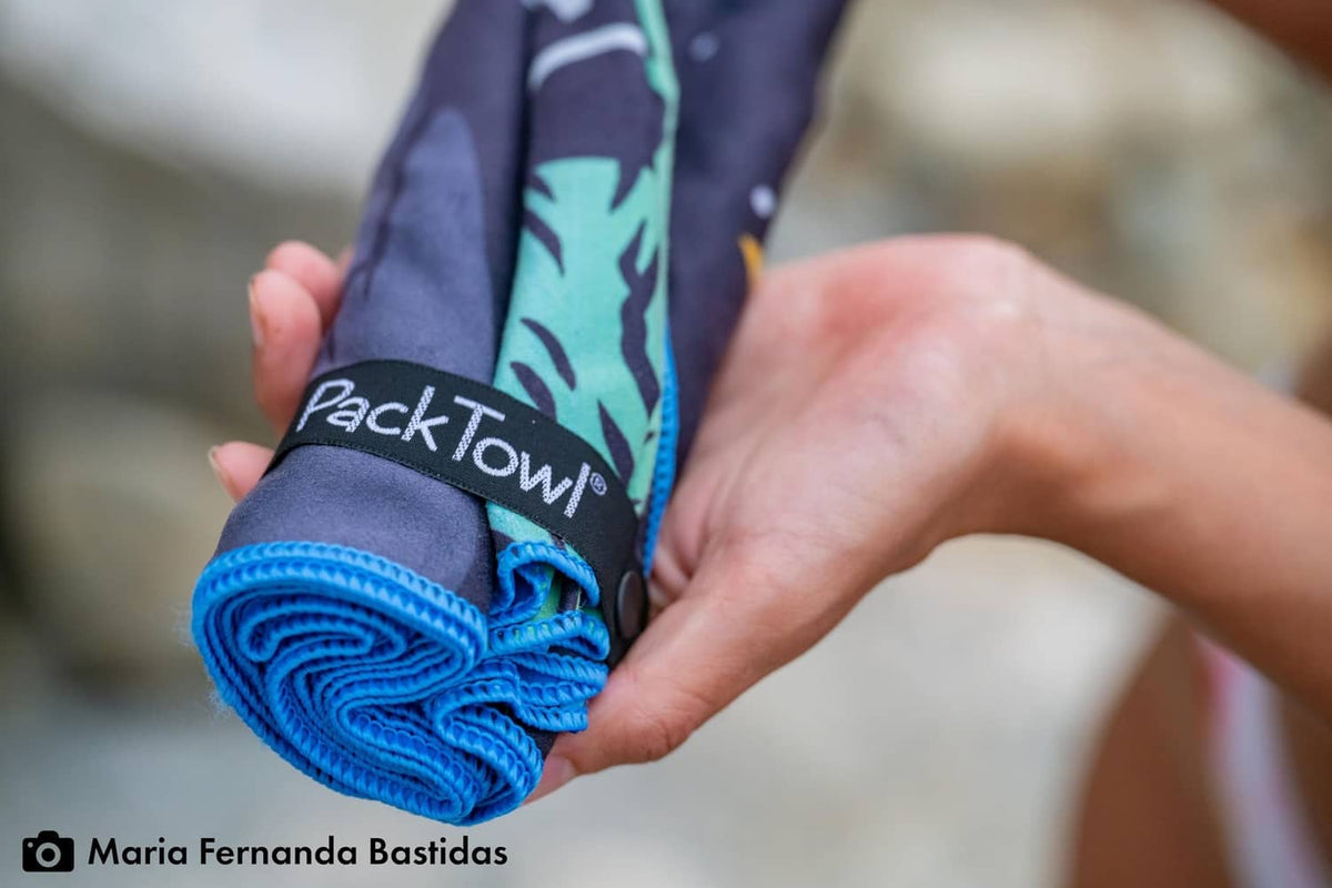 Rolled PackTowl ultralight towel with blue label and patterned purple section.