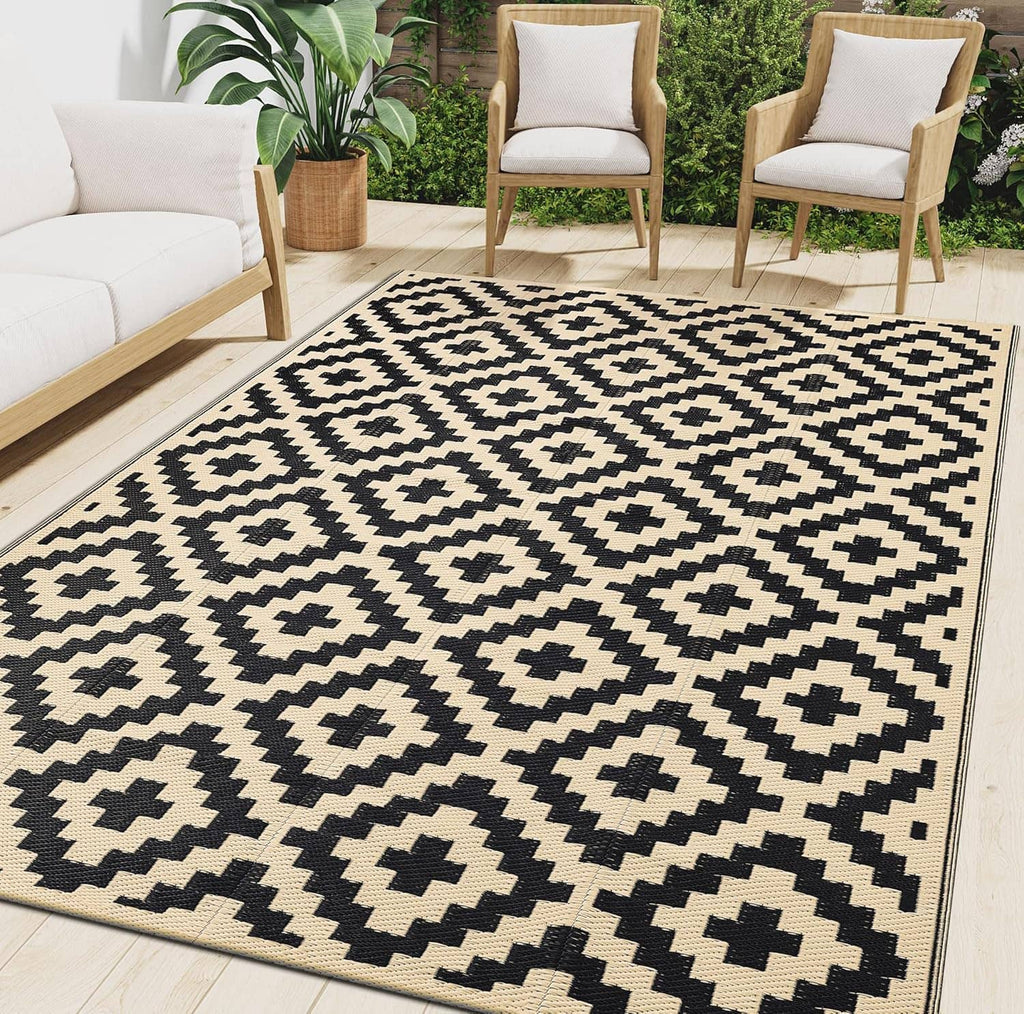 Black and beige geometric outdoor rug with diamond cross pattern and border, low pile.