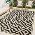 Black and beige geometric outdoor rug with diamond cross pattern and border, low pile.