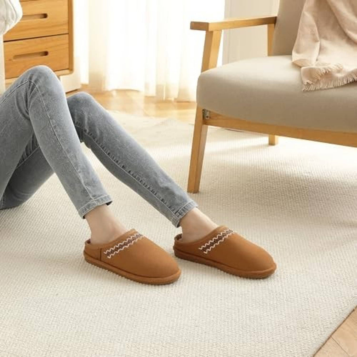Chestnut suede slippers on feet with white faux-fur lining and zigzag stitching