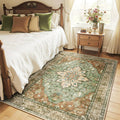 Rectangular floral area rug with green, brown, and brick tones and dark border trim.