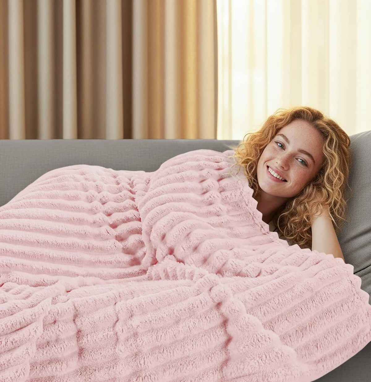 Pink striped fleece blanket covering a woman on a sofa, lounging