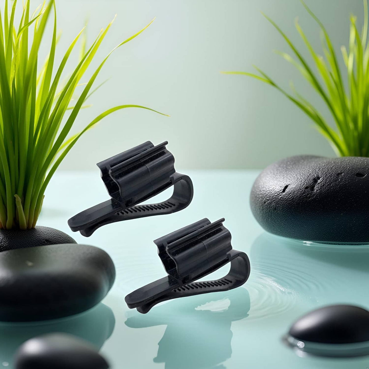 Two black fish tank hose clips with curved holders and ridged base
