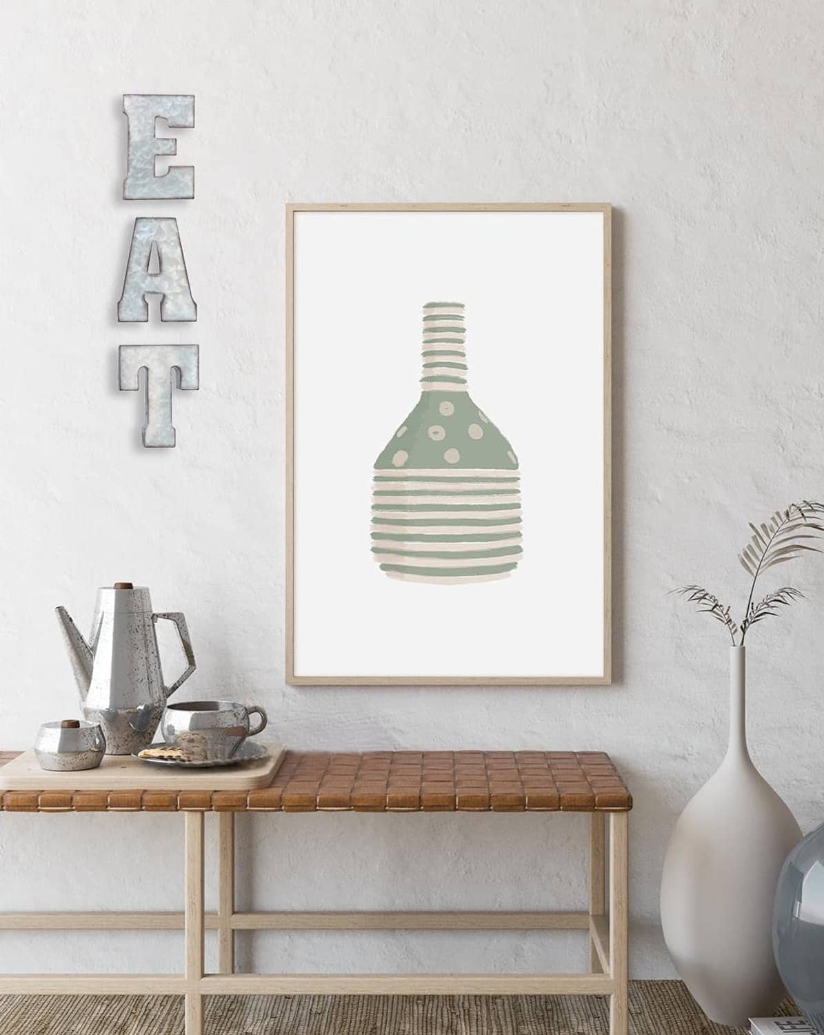 Silver galvanized EAT letter sign on wall beside framed art and vase