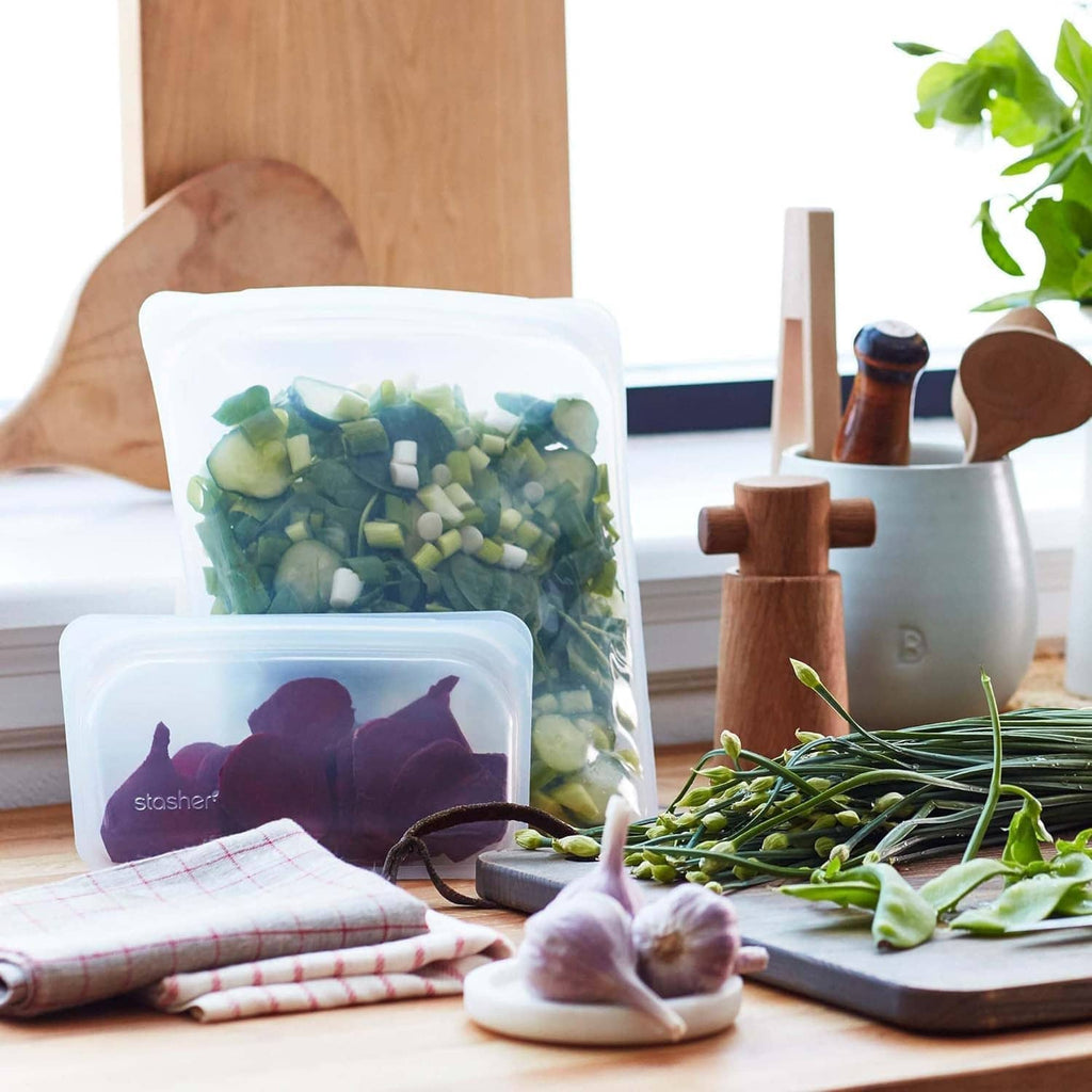 Reusable silicone food storage bags with green vegetables and purple contents on a counter
