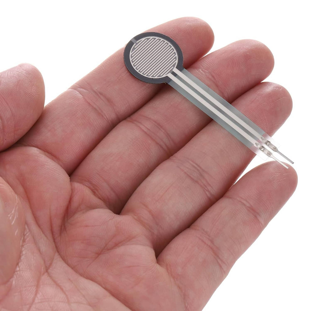 Thin film pressure sensor with round black pad and two silver leads held in hand