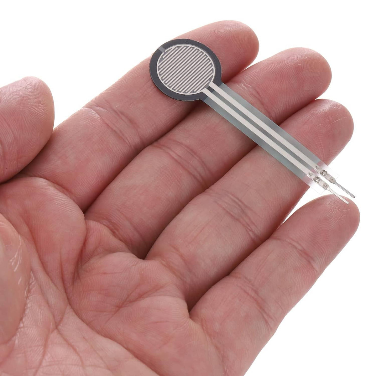 Thin film pressure sensor with round black pad and two silver leads held in hand