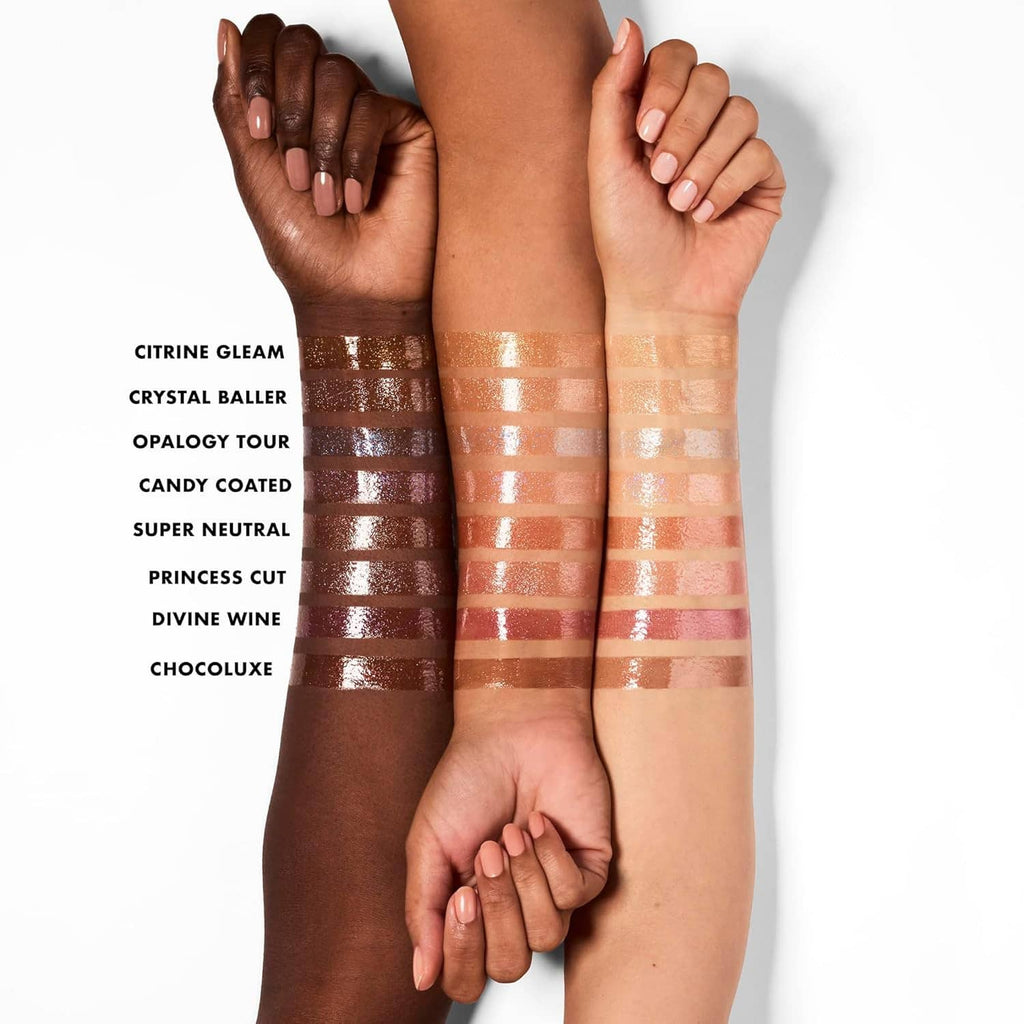 Multiple nude shimmer lip oil swatches on skin in glossy bronze and caramel tones