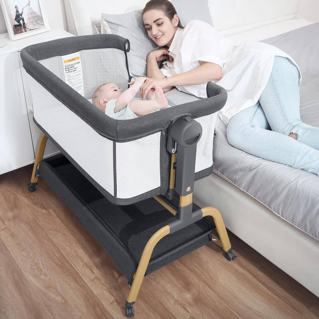 Bedside baby bassinet with gray canopy, white mesh sides, and rocking base undercarriage.