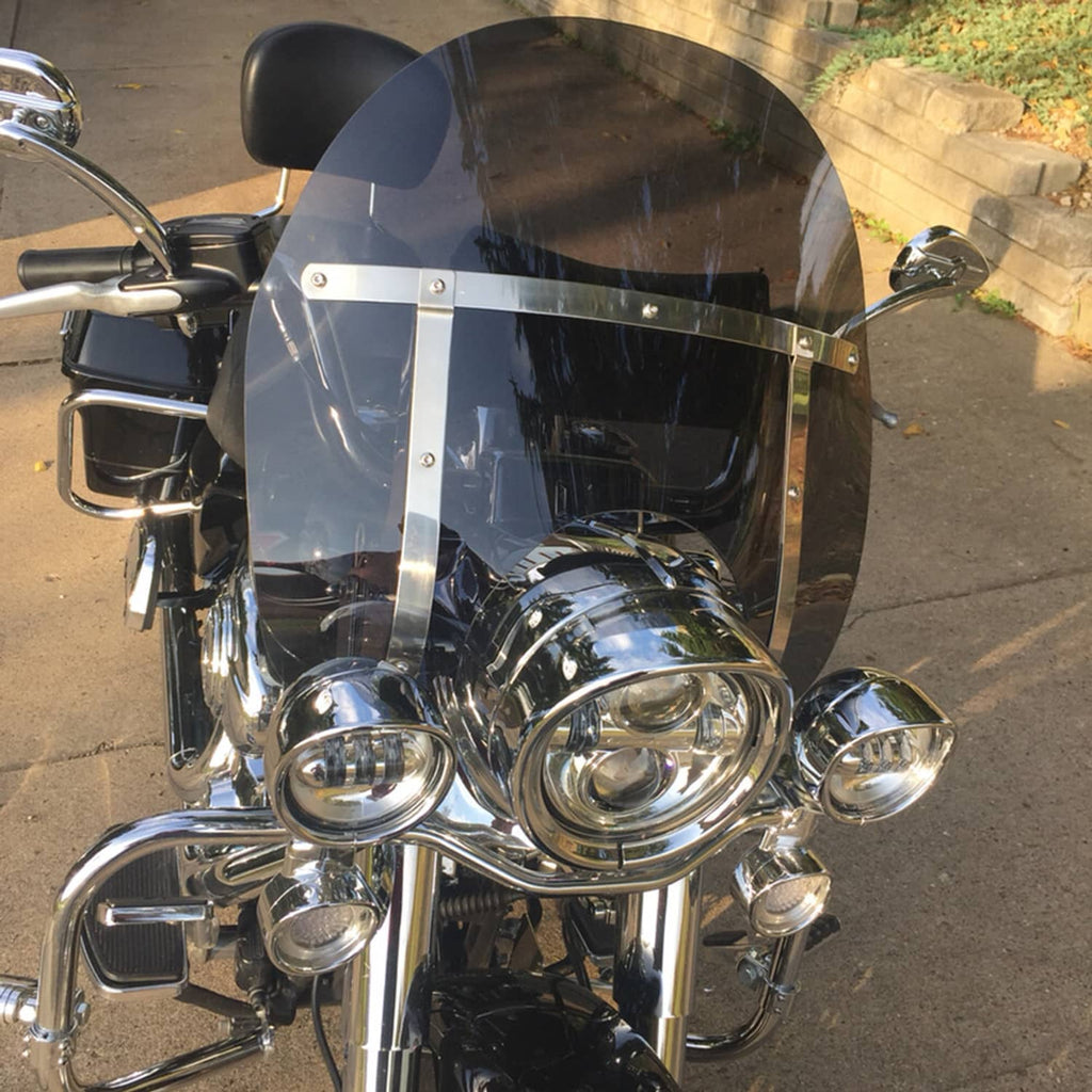 Close-up of smoked dark motorcycle windshield with chrome mounting hardware