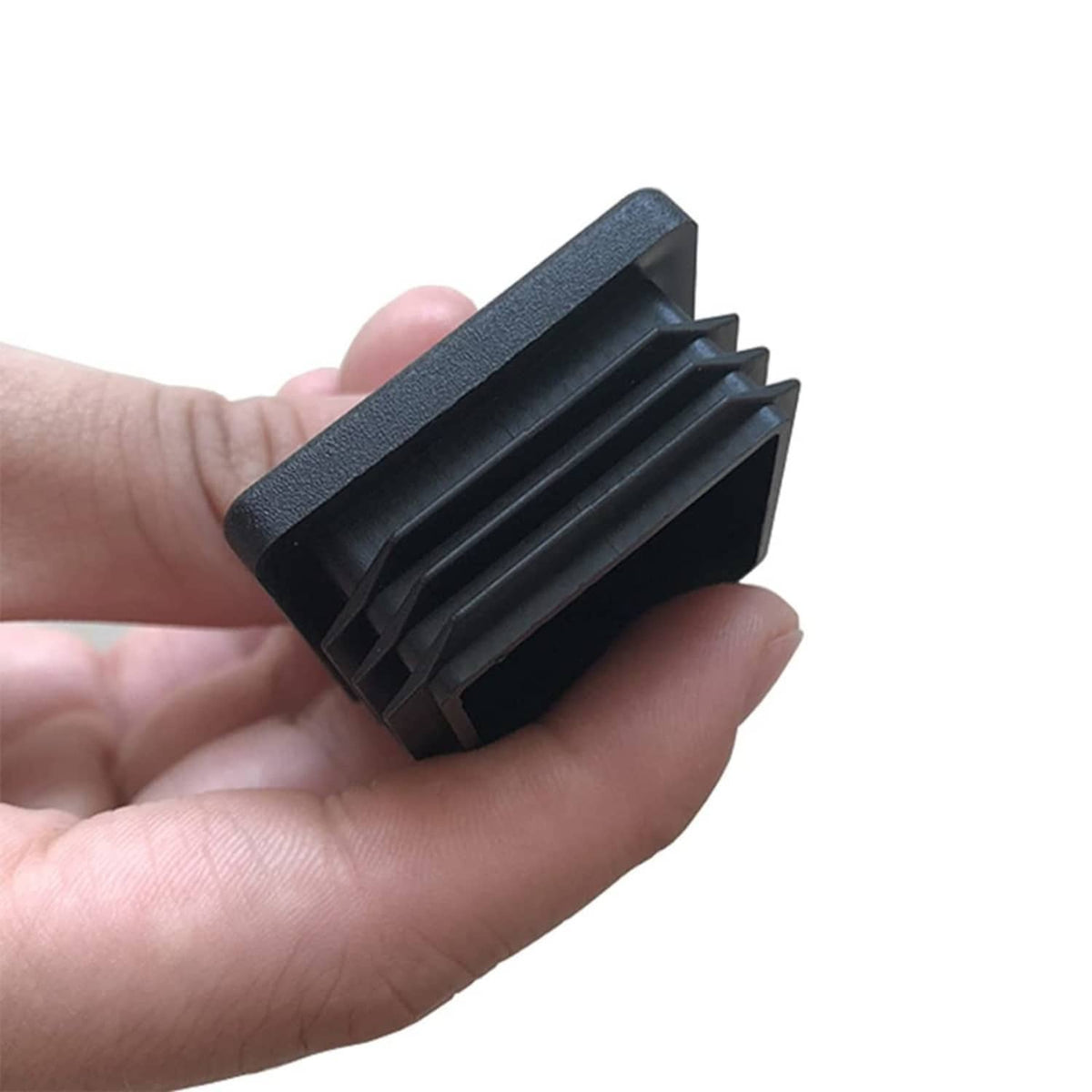 Square plastic tubing end cap, dark, threaded sides shown in hand close-up