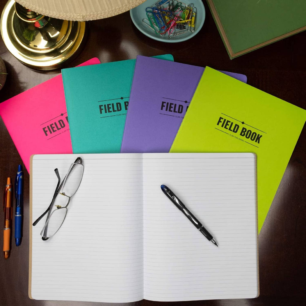 Open field notebook with lined pages and pens, over assorted colorful notebook covers