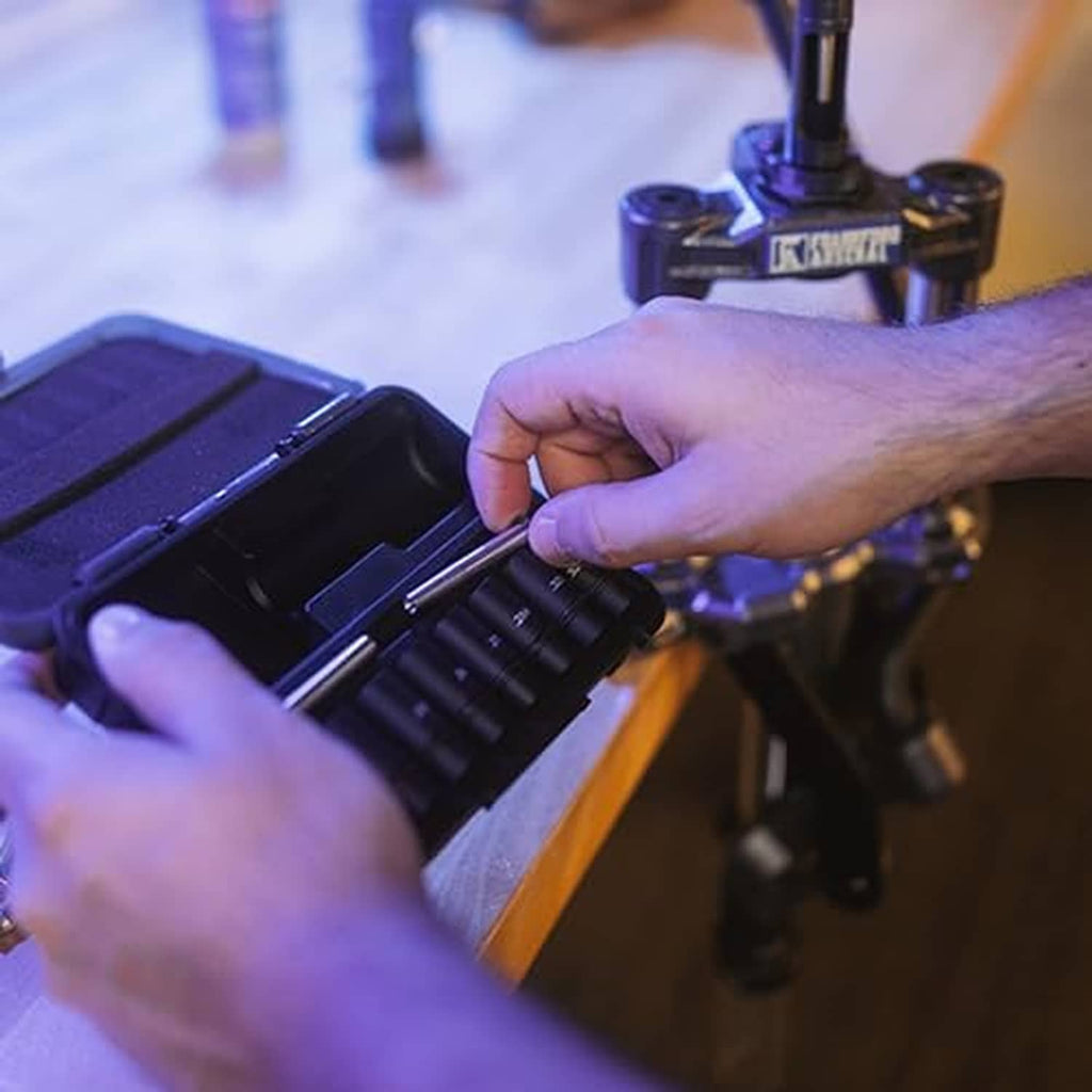 Hands adjusting bullet seating die on reloading press with micrometer control