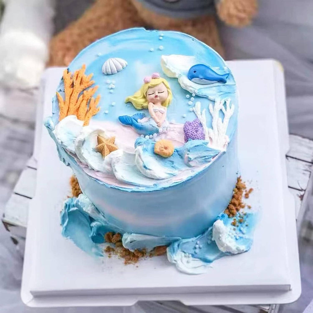 Round blue marine-themed cake with sea-animal decorations and shell accents on top