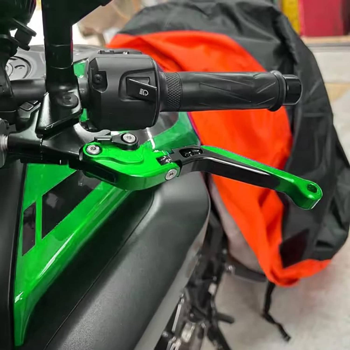 Green motorcycle brake lever on handlebar with black grip and control housing