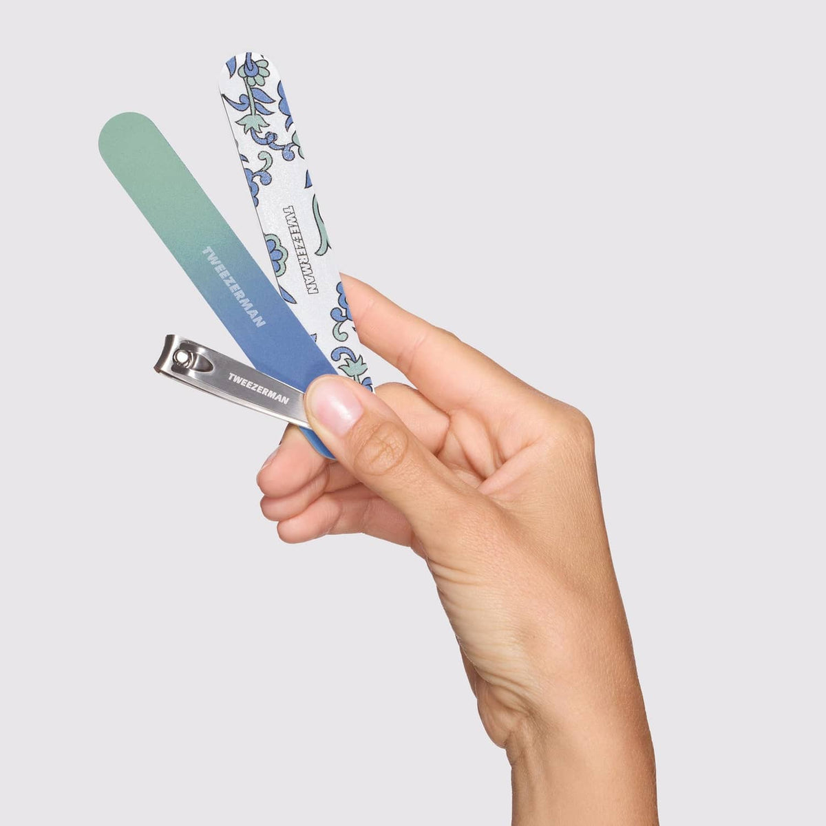 Metal nail clipper with mint and blue files held by hand
