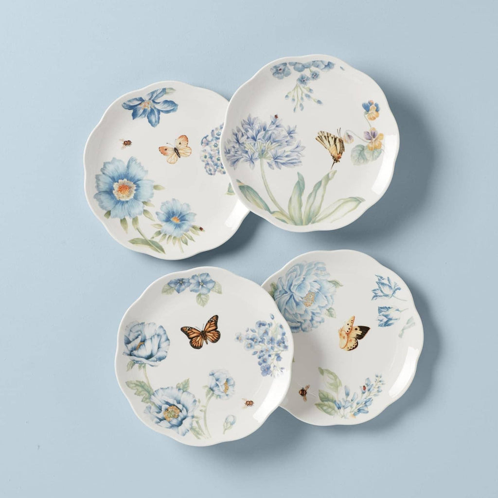 Four round dessert plates featuring blue flowers, butterflies, and green leaves on white.