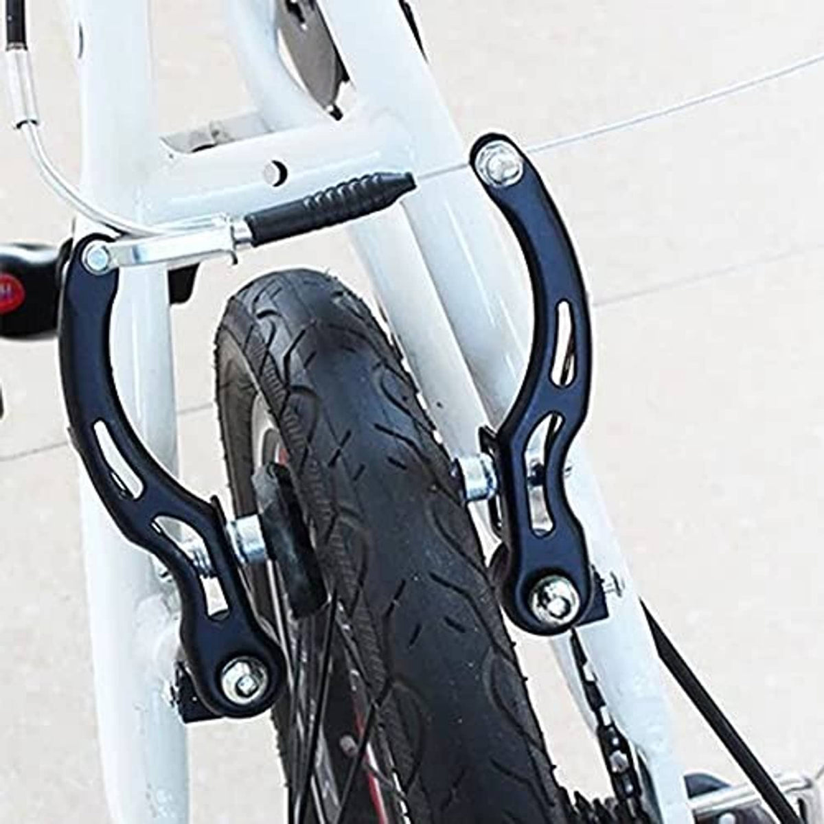 Installed bicycle rim brake caliper with black arms and silver mounting bolts