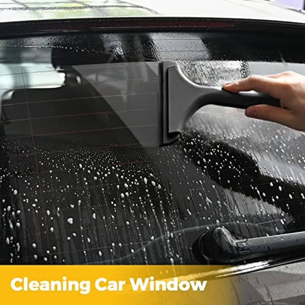 Black squeegee tool wiping water off a car window pane.