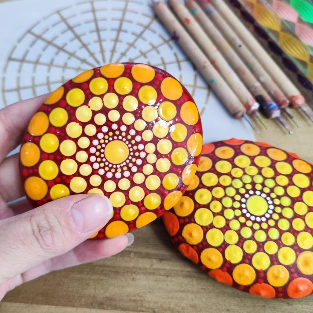 Two painted oval rocks with bright yellow polka-dot patterns held in hands
