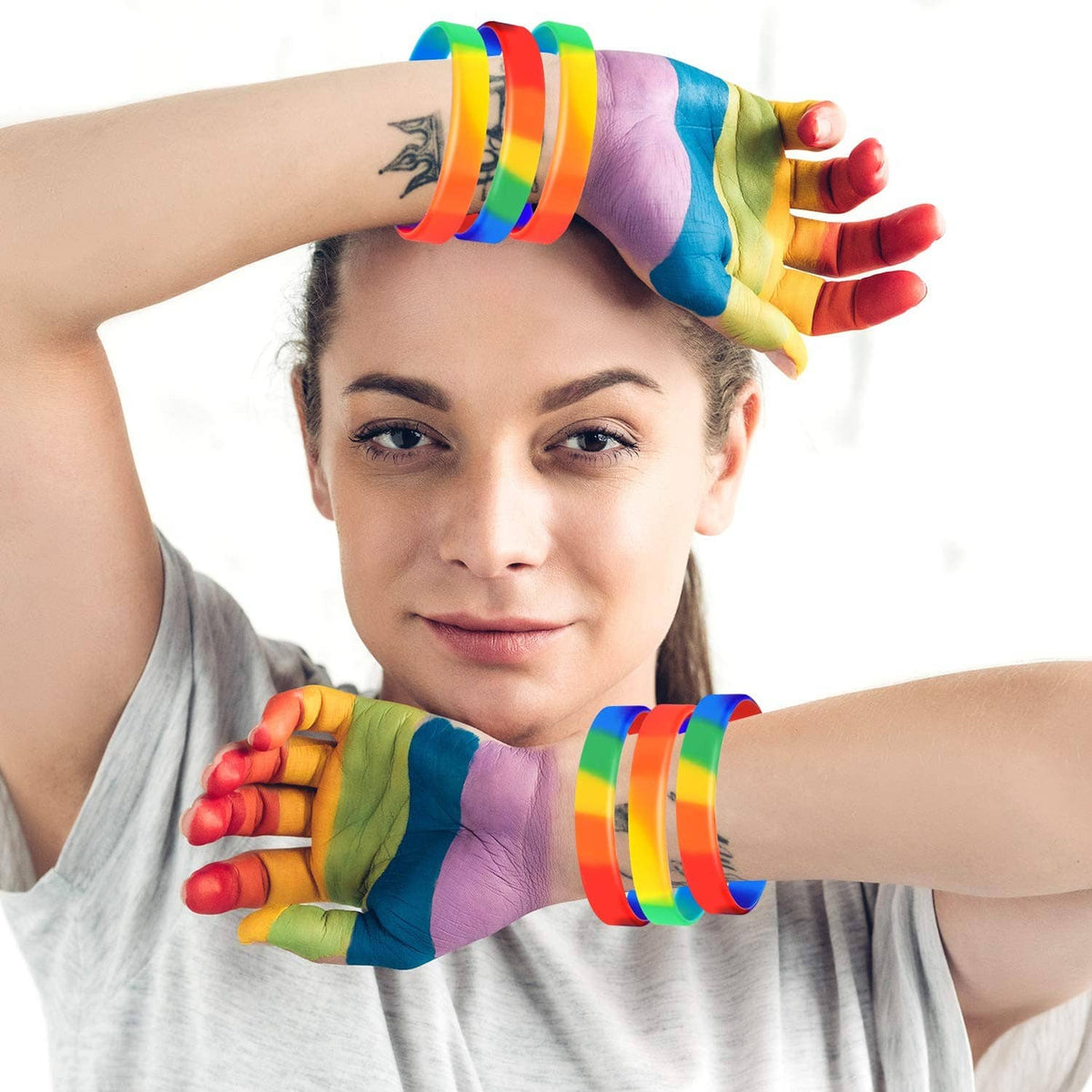Rainbow striped wristbands on arms while wearing a festive hat