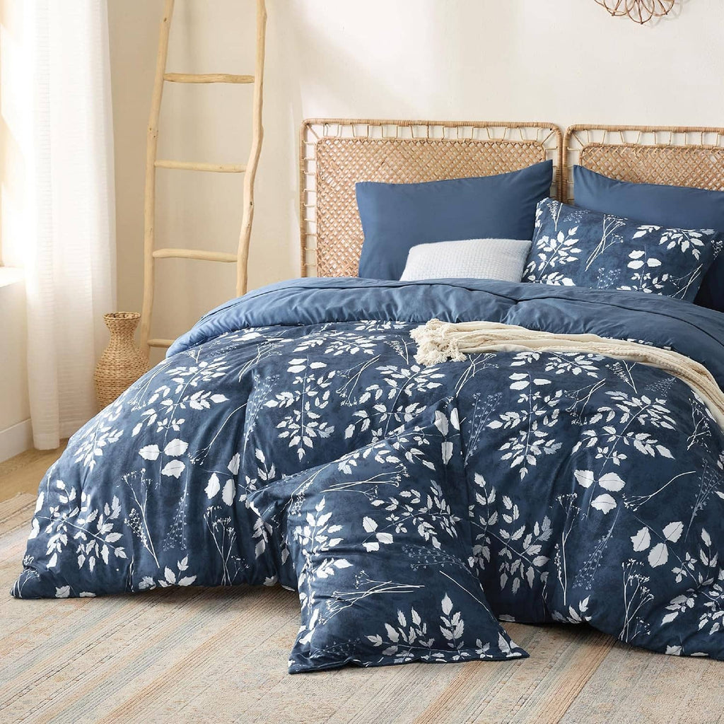Navy floral bedding comforter with pillow shams and stacked pillows on a queen bed