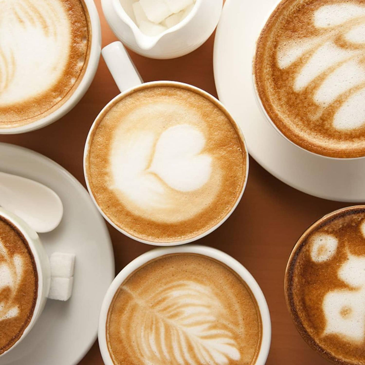 Assorted cappuccino cups with cream and brown foam latte-art shapes