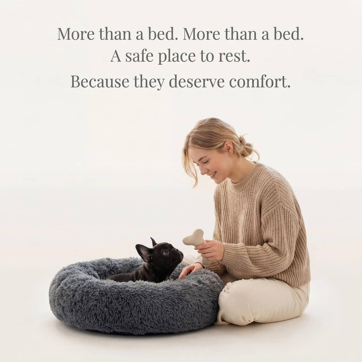 Dark grey round plush dog bed with a small dog resting as a woman comforts it.