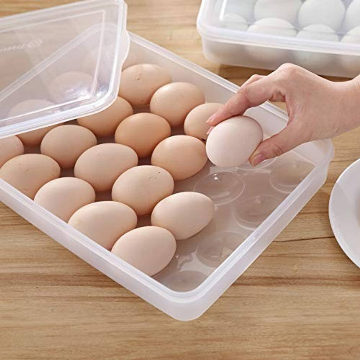 Clear plastic egg holder tray, open lid, brown eggs with hand adjusting