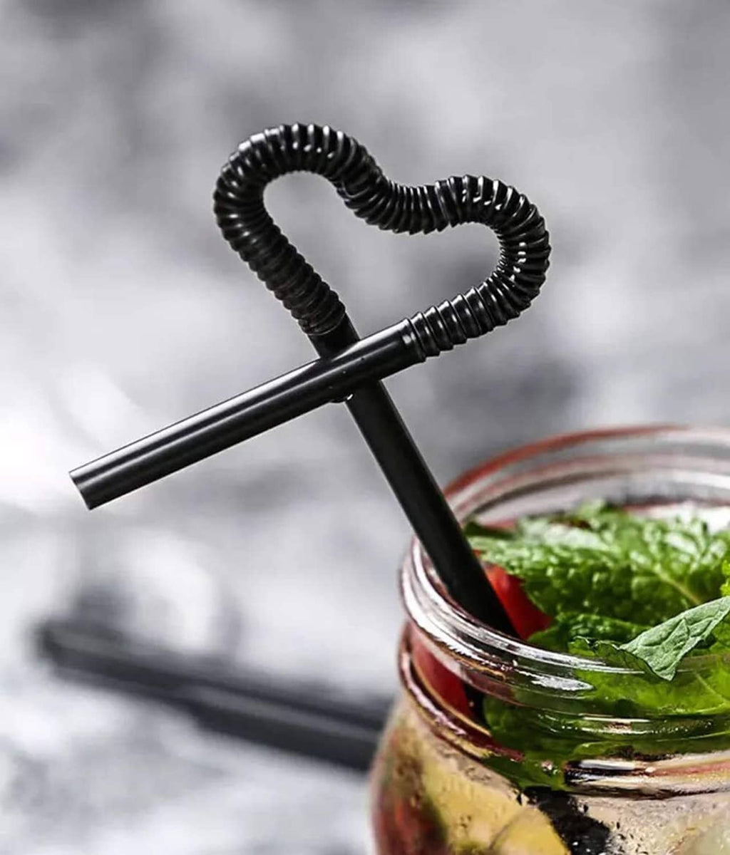 Extra-long black drinking straws with heart-shaped spring curl tips and greenery