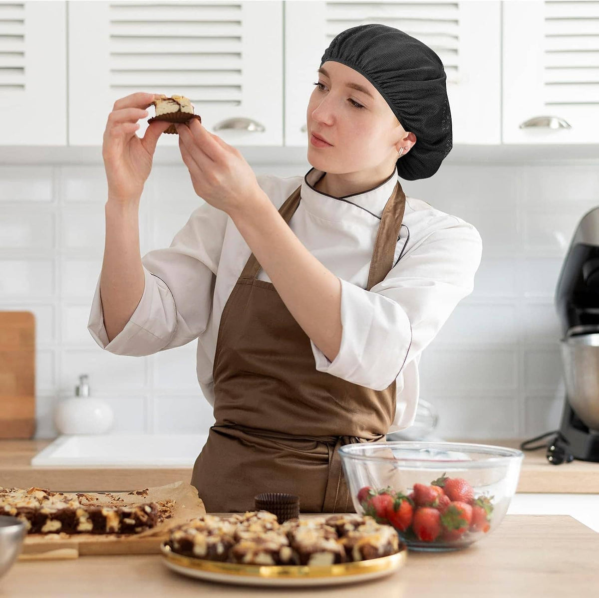 Black hairnet chef cap covering hair on chef in white coat with red buttons