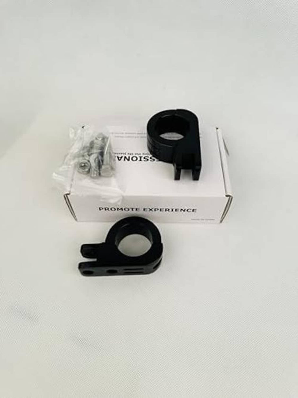 Black foot peg mounting clamps with bagged hardware beside product box