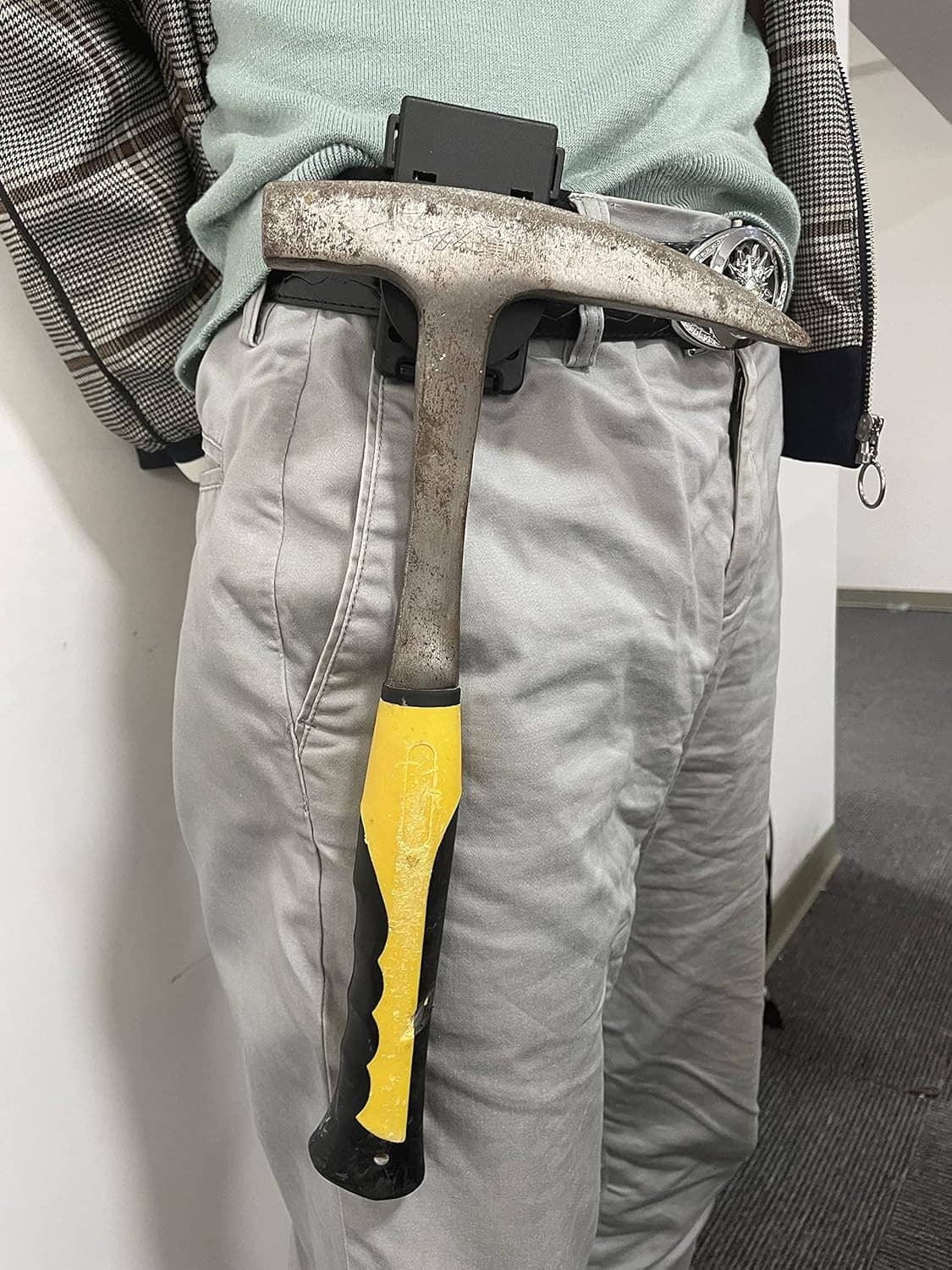 Magnetic belt holster on work pants holding a hammer and pry bar